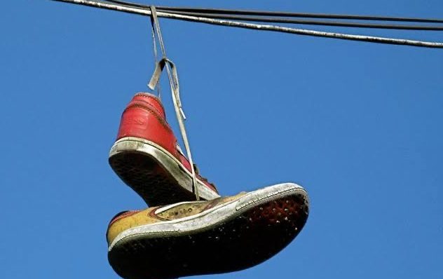 Pair of old shoes or sneakers hanging from a power line by the laces Stock  Photo - Alamy